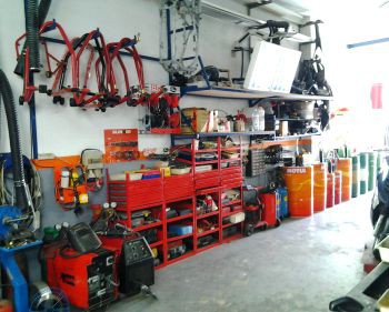 Zona de taller con estanterías, compresores y consumibles